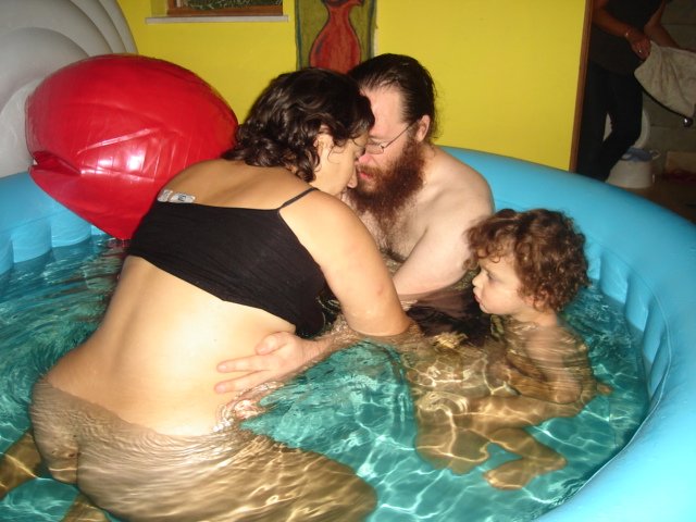 giving birth in the bath with family and child in the water